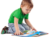 boy looking at a picture book on the floor