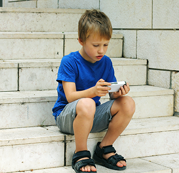 boy on stairs with electronic game