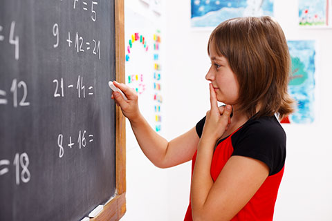 girl doing a math problem at chalkboard