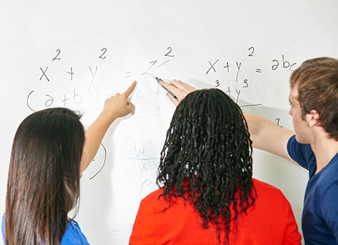three student working math problem at whiteboard