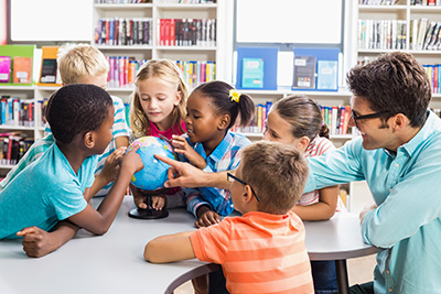 teacher and students examine globe