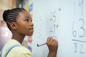 Girl solving math problem on whiteboard