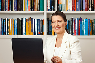 woman at desk in home library with laptop