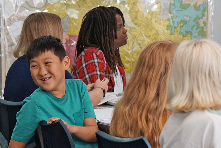 Asian boy turned around in seat while other students face forward