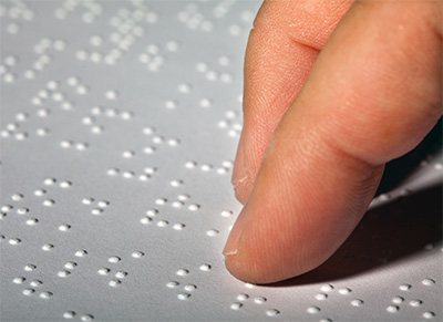 fingers on a sheet of braille dots