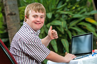 young man with a laptop giving a thumbs up